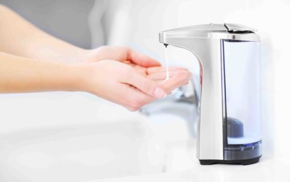 Close up of female hands using automatic soap dispenser